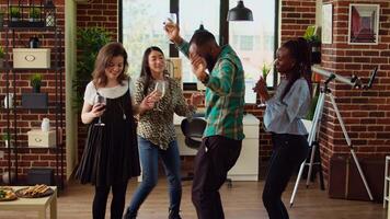 multiraciaal school- collega's organiserende appartement partij, enthousiast dansen naar elektronisch muziek. glimlachen vrienden genieten van tijd uitgegeven samen, kapot maken in dynamisch dans beweegt video