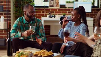 gelukkig Afrikaanse Amerikaans Mens Bij appartement partij bespreken met glimlachen vrouw, flirten met haar. gast in elegant leven kamer geïnteresseerd in charmant bipoc gastheer, hebben gesprek met haar video