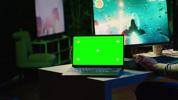 Mockup laptop next to man playing high FPS singleplayer videogame with spaceship shooting laser streams at asteroid. Green screen notebook near gamer using crosshair overlay to hit targets in SF game video