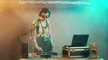 DJ performer creating techno music at control buttons, wearing crazy makeup and mixing at audio stereo equipment. Artist playing disco sounds at turntables for nightclub party event. Tripod shot. video