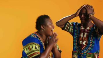 Cheerful african american couple laughing at thing in studio, having fun with jokes and being amused over background. Married ethnic people enjoying laugh on camera, joyful partners. video