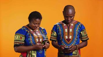 Ethnic couple waving hello on online videocall connection, using internet network and video link to chat with family members. Husband and wife holding smartphone to talk to people on web.