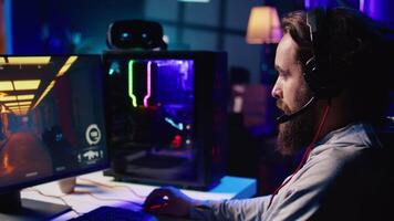 Man using headphones microphone to talk with teammates while playing FPS videogame with gun shooting laser bullets. Gamer chatting with internet friends while enjoying SF game, close up video
