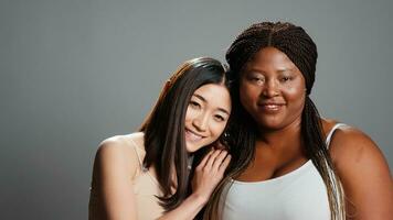 Cheerful diverse models laughing and hugging in studio, enjoying wellness and expressing body positivity. Healthy women feeling confident and positive, skinny and curvy body types. photo