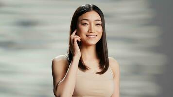 Asian lady doing empowering beauty campaign for self love, promoting natural skincare routine in studio. Young flawless model being gentle and elegant, feeling confident about imperfections. photo