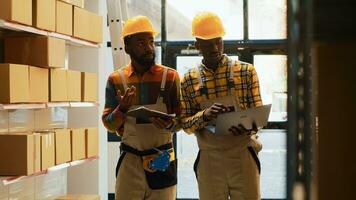 Team of men checking supplies and cargo in depot, using laptop and inventory list in storage room. Workers organizing stock with cardboard boxes on shelves, check merchandise in warehouse. photo