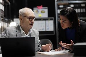 Administrative management coworking businessmen discussing accountancy market database information. Invoicing paperwork in archival cabinet room office filled with document folders and flowcharts photo