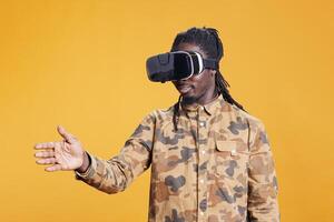 Confident person using virtual reality goggles, enjoying playing with virtual reality glasses to see 3d visual simulation. African american man wearing modern goggles to use futuristic technology. photo