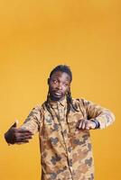 Stylish entrepreneur running late and looking at clock, being impatient about punctuality waiting for someone in studio, African american manager checking time on wristwatch standing over background photo