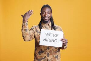 African american manager holding paper to make job offer in front of camera, hiring perfect candidate for career opportunity. Hr employee asking people to attend job interview in studio photo