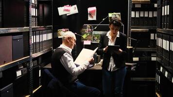 Experts team review evidence reports together with classified documents, gathering intelligence and incriminating proof. Inspector and agent taking notes to for private investigation. photo