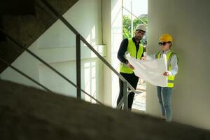 Engineer and architect working on the construction site, double-checking plans and process. photo