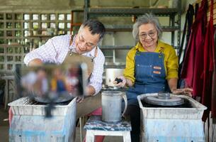 Asian retired couple with pottery making and clay painting activities in the pottery workshop with live broadcasting via social media channels photo