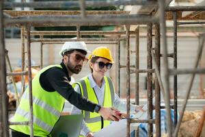 Engineer and architect working on the construction site, double-checking plans and process. photo