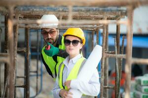 Engineer and architect working on the construction site, double-checking plans and process. photo