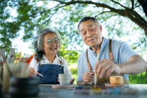 In the pottery workshop, an Asian retired couple is engaged in pottery making and clay painting activities. photo