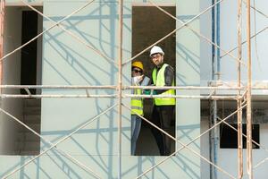 Engineer and architect working on the construction site, double-checking plans and process. photo