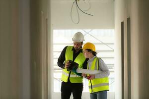 Engineer and architect working on the construction site, double-checking plans and process. photo