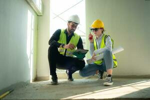 Engineer and architect working on the construction site, double-checking plans and process. photo