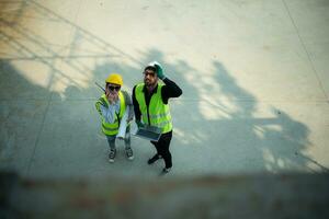 Overhead view on a building site, an engineer and architect are discussing on a laptop. photo