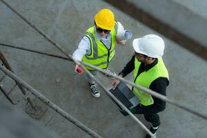 Overhead view on a building site, an engineer and architect are discussing on a laptop. photo