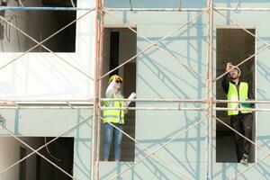 Engineer and architect working on the construction site, double-checking plans and process. photo
