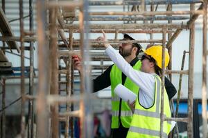 Engineer and architect working on the construction site, double-checking plans and process. photo