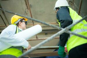 Engineer and architect working on the construction site, double-checking plans and process. photo