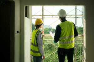 Engineer and architect working on the construction site, double-checking plans and process. photo