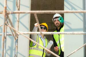 Engineer and architect working on the construction site, double-checking plans and process. photo