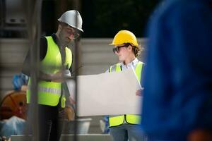 Engineer and architect working on the construction site, double-checking plans and process. photo