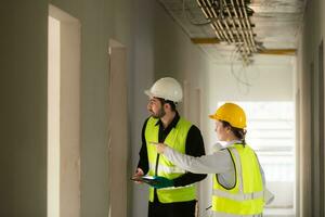 Engineer and architect working on the construction site, double-checking plans and process. photo