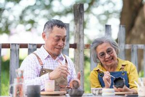 en el cerámica taller, un asiático retirado Pareja es comprometido en cerámica haciendo y arcilla pintura actividades. foto