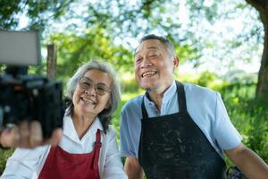 Asian retired couple with pottery making and clay painting activities in the pottery workshop with live broadcasting via social media channels photo