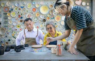 en el cerámica taller, un asiático retirado Pareja es comprometido en cerámica haciendo y arcilla pintura actividades. foto