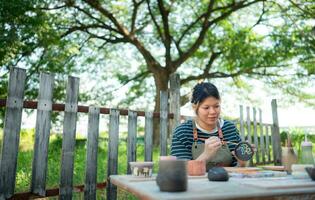 In the pottery workshop, Asian woman is engaged in pottery making and clay painting activities. photo