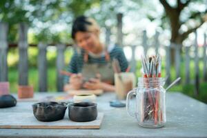 In the pottery workshop, Asian woman is engaged in pottery making and clay painting activities. photo