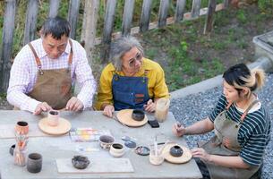 In the pottery workshop, an Asian retired couple is engaged in pottery making and clay painting activities. photo