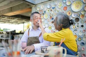 In the pottery workshop, an Asian retired couple is engaged in pottery making and clay painting activities. photo