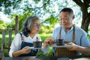 In the pottery workshop, an Asian retired couple is engaged in pottery making and clay painting activities. photo