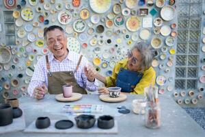 en el cerámica taller, un asiático retirado Pareja es comprometido en cerámica haciendo y arcilla pintura actividades. foto