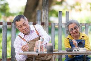 en el cerámica taller, un asiático retirado Pareja es comprometido en cerámica haciendo y arcilla pintura actividades. foto