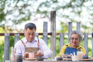 en el cerámica taller, un asiático retirado Pareja es comprometido en cerámica haciendo y arcilla pintura actividades. foto