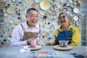 In the pottery workshop, an Asian retired couple is engaged in pottery making and clay painting activities. photo