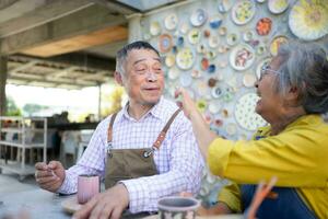 In the pottery workshop, an Asian retired couple is engaged in pottery making and clay painting activities. photo