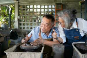 Portrait of a senior Asian couple doing activities together in the pottery workshop. photo