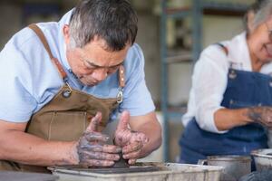 Portrait of a senior Asian couple doing activities together in the pottery workshop. photo