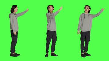 Person indicating left or right directions on camera, pointing to both sides and recommending another path. Asian friendly man advising people to go this way using index fingers, greenscreen. video