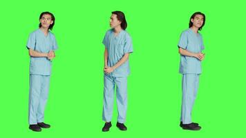 medicinsk specialist väntar och ser för något över grönskärm studio, bär klinik enhetlig och varelse otålig. sjuksköterska läkare med sjukvård expertis, wellness ockupation. video