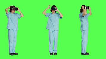 ung sjuksköterska använder sig av virtuell verklighet headsetet mot grönskärm bakgrund, arbetssätt med modern interaktiv 3d glasögon. medicinsk sjukvård assistent arbetssätt med artificiell intelligens. video